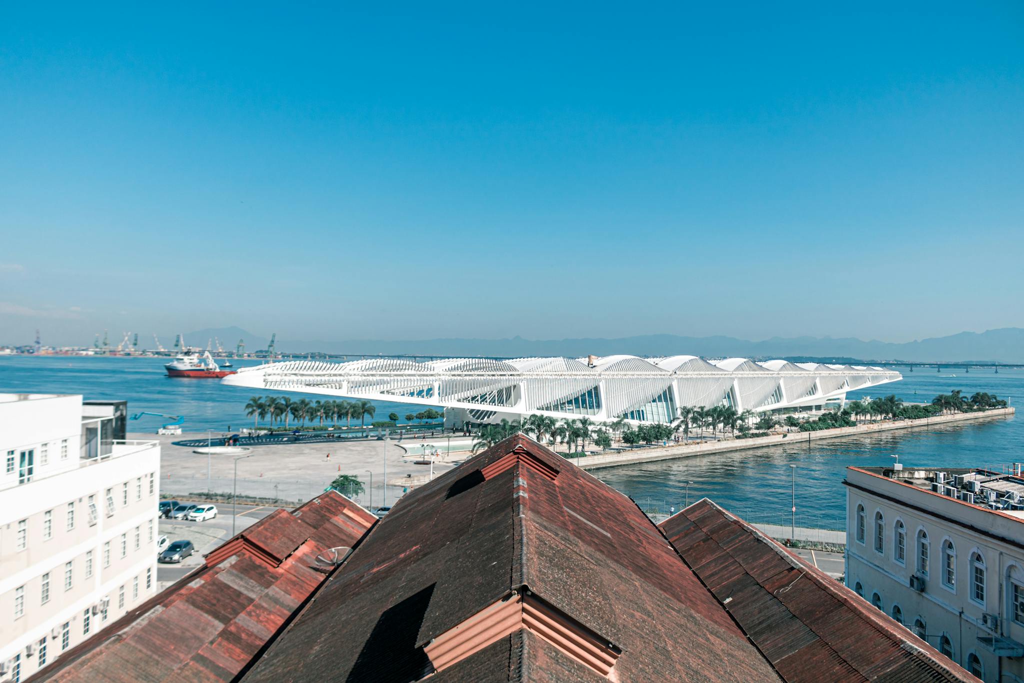 A breathtaking aerial view of the Museum of Tomorrow and waterfront in Rio de Janeiro under a clear blue sky.