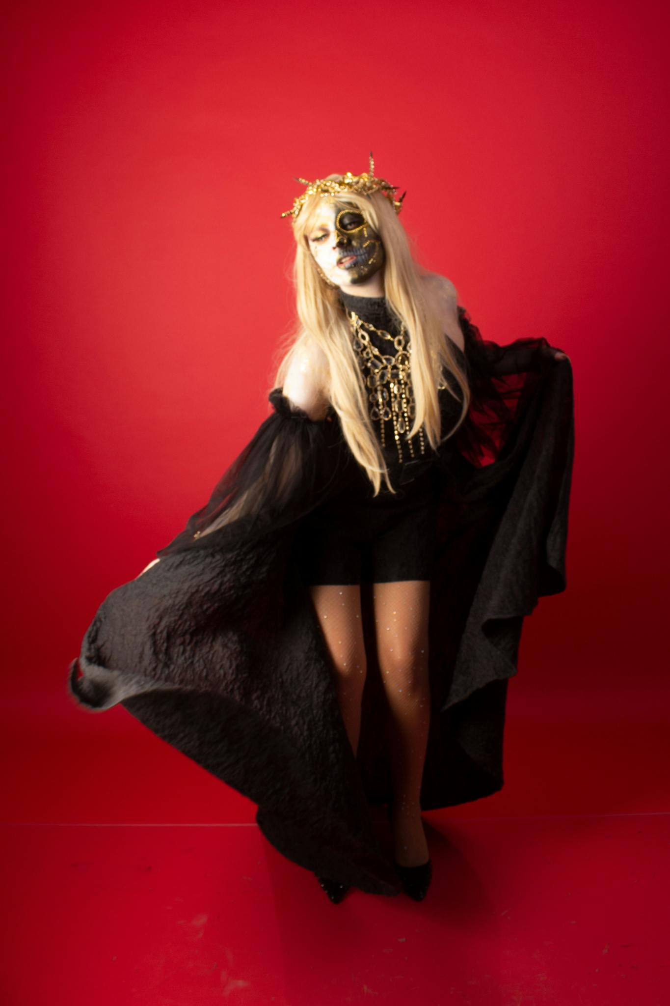 Stunning Dia de Muertos costume portrait with intricate makeup on a vivid red background.